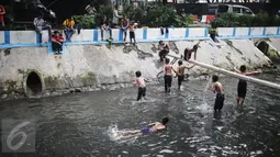 Anak-anak berenang dan bermain air di aliran Kali Gresik di Jalan Muhammad Yamin, Menteng, Jakarta, Minggu (26/2). (Liputan6.com/Faizal Fanani)