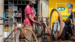 Seorang pria memperbaiki sepeda di Kampala, ibu kota Uganda (30/6/2020). Warga Uganda kini beralih menggunakan sepeda sebagai sarana transportasi yang mendukung di tengah pandemi COVID-19. (Xinhua/Hajarah Nalwadda)