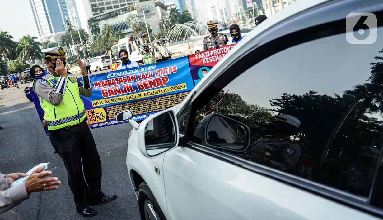 Petugas kepolisian membentangkan spanduk saat sosialisasi pelaksanaan ganjil genap di Kawasan Bundaran HI, Jakarta, Minggu (2/8/2020). Ditlantas Polda Metro Jaya kembali memberlakukan sistem ganjil genap di 25 ruas jalan protokol  DKI Jakarta mulai Senin, 3 Agustus 2020. (Liputan6.com/Faizal Fanani)