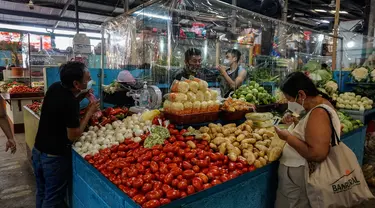 Pelanggan membeli sayuran di sebuah kios dengan sekat tirai pelindung plastik di pasar La Asuncion di Villa Nueva, Guatemala City pada 20 Juli 2020. Kios di pasar itu menggunakan tirai pelindung plastik untuk menjaga jarak fisik guna mengurangi resiko penyebaran virus Corona. (Johan ORDONEZ/AFP)