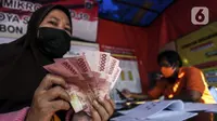 Warga menunjukkan uang bantuan sosial (bansos) di kawasan Kedoya Selatan, Jakarta Barat, Rabu (28/7/2021). Bansos berupa uang tunai sebesar Rp 600 ribu tersebut disalurkan oleh PT. Pos Indonesia. (Liputan6.com/Johan Tallo)