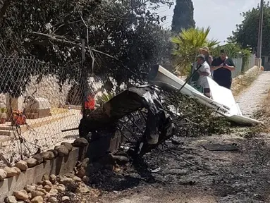 Puing-puing bekas tabrakan antara sebuah helikopter dan pesawat kecil terlihat di jalan dekat Mallorca, Spanyol, Minggu (26/8/2019). Setidaknya tujuh orang tewas, termasuk dua anak di bawah umur, dalam insiden tabrakan udara tersebut. (Incendios f.Baleares via AP)