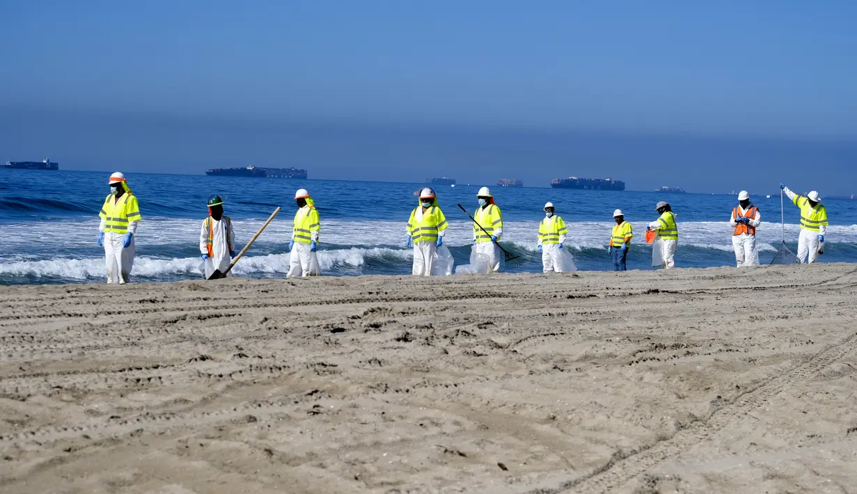 Pekerja dengan pakaian pelindung membersihkan pantai yang terkontaminasi tumpahan minyak di Huntington Beach, California, Amerika Serikat, Selasa (5/10/2021). Kebocoran pipa menyebabkan tumpahan minyak di lepas pantai California. (AP Photo/Ringo H.W. Chiu)