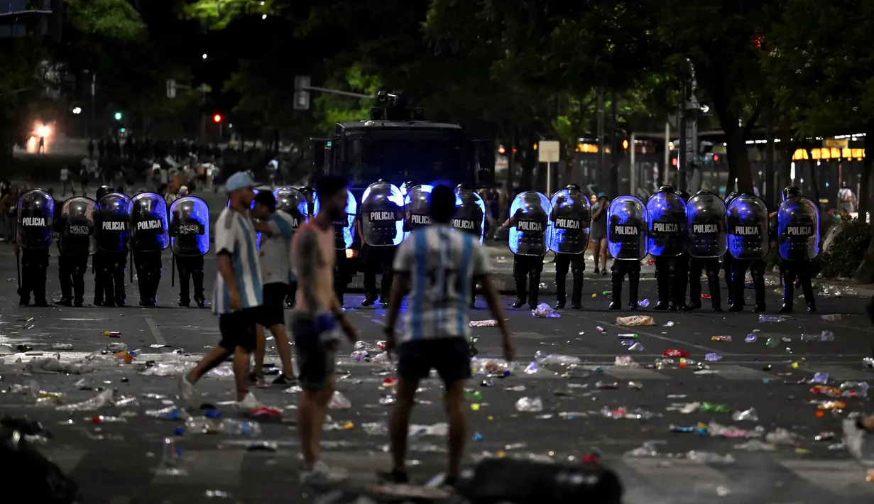 Polisi anti huru hara berjaga-jaga setelah bentrok dengan suporter Argentina setelah perayaan timnas Argentina meraih juara Piala Dunia Qatar 2022 di lingkungan Obelisk di Buenos Aires (20/12/2022). Kerusuhan pecah pukul 20.00 malam. Kericuhan bermula saat petugas hendak membubarkan penggemar yang membobol struktur dan memanjat monumen Obelisk. (AFP/Luis Robayo)