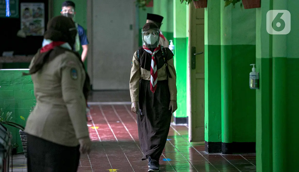 Siswa menjaga jaga saat akan memasuki ruang kelas pada pada hari pertama uji coba Pembelajaran Tatap Muka (PTM) di SDN Kenari 08 Pagi Jakarta, Rabu (7/4/2021). Pemprov DKI Jakarta mulai melakukan uji coba pembelajaran tatap muka secara terbatas di 100 sekolah. (Liputan6.com/Faizal Fanani)