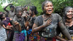 Sejumlah wanita Bali terlihat bergembira saat mengikuti tradisi mandi lumpur di desa Kedonganan, Denpasar, Bali (10/3). Mebuug-buugan bertujuan untuk menetralkan sifat-sifat buruk usai hari raya Nyepi. (AFP/Sonny Tumbelaka)