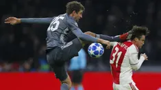 Gelandang Bayern Munchen, Thomas Mueller, menendang kepala bek Ajax Amsterdam, Nicolas Tagliafico, pada laga Liga Champions di Johan Cruyff Arena, Amsterdam, Rabu (12/12). Kedua tim bermain imbang 3-3. (AP/Peter Dejong)
