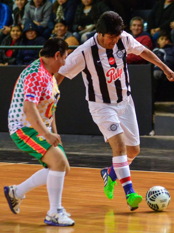 Presiden Bolivia Evo Morales menggiring bola saat pertandingan persahabatan melawan anggota komunitas Bolivia setempat selama kunjungannya di Asunción, Paraguay, (14/8). (AFP Photo/Silvio Rojas)