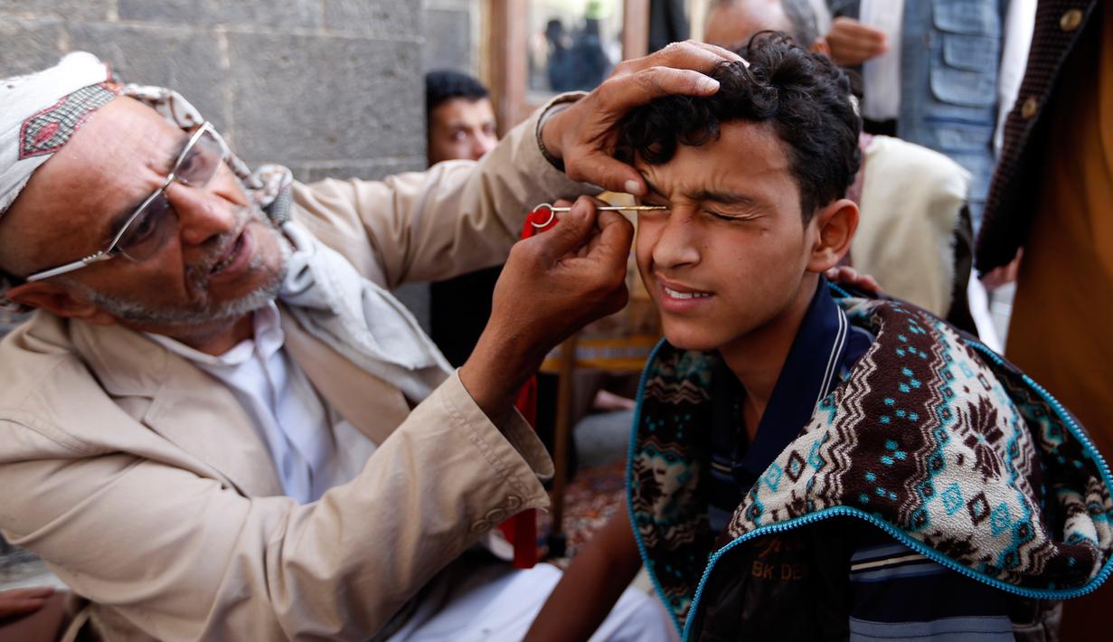 Ekspresi seorang pria saat kelopak matanya dirias dengan kohl atau celak di  Masjid Agun di kota tua ibukota Sanaa, Yama, (19/5). Pemakaian kohl atau celak ini sudah menjadi tradisi muslim Yaman pada setiap bulan Ramadan. (AFP Photo/Mohammed Huvais)