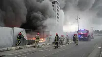 Petugas pemadam kebakaran berusaha memadamkan api di pusat logistik yang rusak setelah penembakan di Kiev, Ukraina, Kamis (3/3/2022). Rusia telah meluncurkan serangan jarak jauh ke Ukraina, menghantam kota dan pangkalan dengan serangan udara atau penembakan. (AP Photo/Efrem Lukatsky)