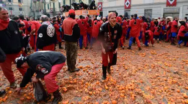 Peserta berjalan di atas tumpukan jeruk yang hancur pada festival "Battaglia delle Arance" (Perang Jeruk) di sebuah kota kecil di Provinsi Turin, Italia, Minggu (11/2). Tradisi melempar jeruk dilakukan selama tiga hari pada Februari. (MIGUEL MEDINA/AFP)