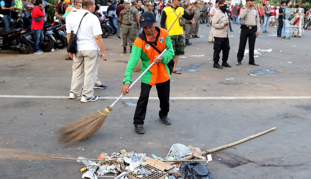 Petugas PPSU membersihkan sampah sisa perayaan Hari Buruh Internasional di kawasan Silang Barat Daya Monas, Jakarta, Rabu (1/5). Sampah yang berserakan di kawasan tersebut membuat Petugas PPSU bekerja ekstra keras untuk membersihkan kawasan tersebut. (Liputan6.com/Helmi Fithriansyah)