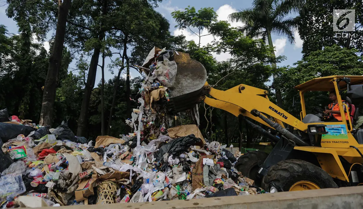 Petugas kebersihan dibantu alat berat membersihkan sampah Tahun Baru 2018 di Monas, Jakarta, Senin (1/1). Setelah perayaan malam tahun baru 2018, sampah sisa pengunjung berserakan di lokasi perayaan. (Liputan6.com/Faizal Fanani)