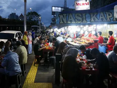 Warga menikmati waktu serta menu berbuka puasa di Sentra Kuliner Nasi Kapau di Jalan Kramat Raya, Senen, Jakarta, Senin (17/3/2025). (Liputan6.com/Herman Zakharia)
