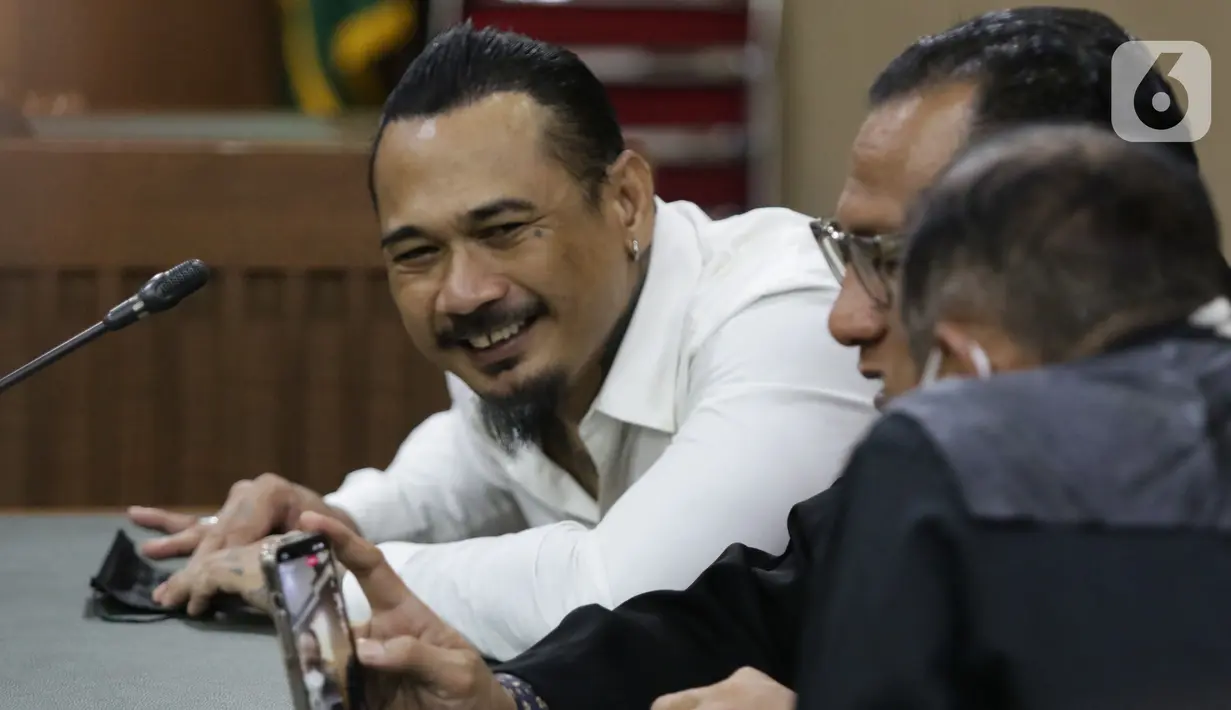 Musisi I Gede Ari Astina alias Jerinx SID (kiri) sesaat sebelum sidang pembacaan putusan kasus dugaan pengancaman terhadap Adam Deni di PN Jakarta Pusat, Kamis (24/2/2022). I Gede Ari Astina divonis satu tahun penjara, denda Rp 25 juta subsider satu bulan kurungan. (Liputan6.com/Helmi Fithriansyah)