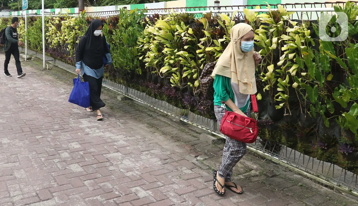 Sejumlah pasien Covid-19 berjalan memasuki bus sekolah di Puskesmas Kecamatan Ciracas, Jakarta, Kamis (10/06/2021). Kasus positif di Jakarta bertambah 2.096 orang, sehingga total kasus positif bertambah menjadi 440.554 orang. (Liputan6.com/Herman Zakharia)