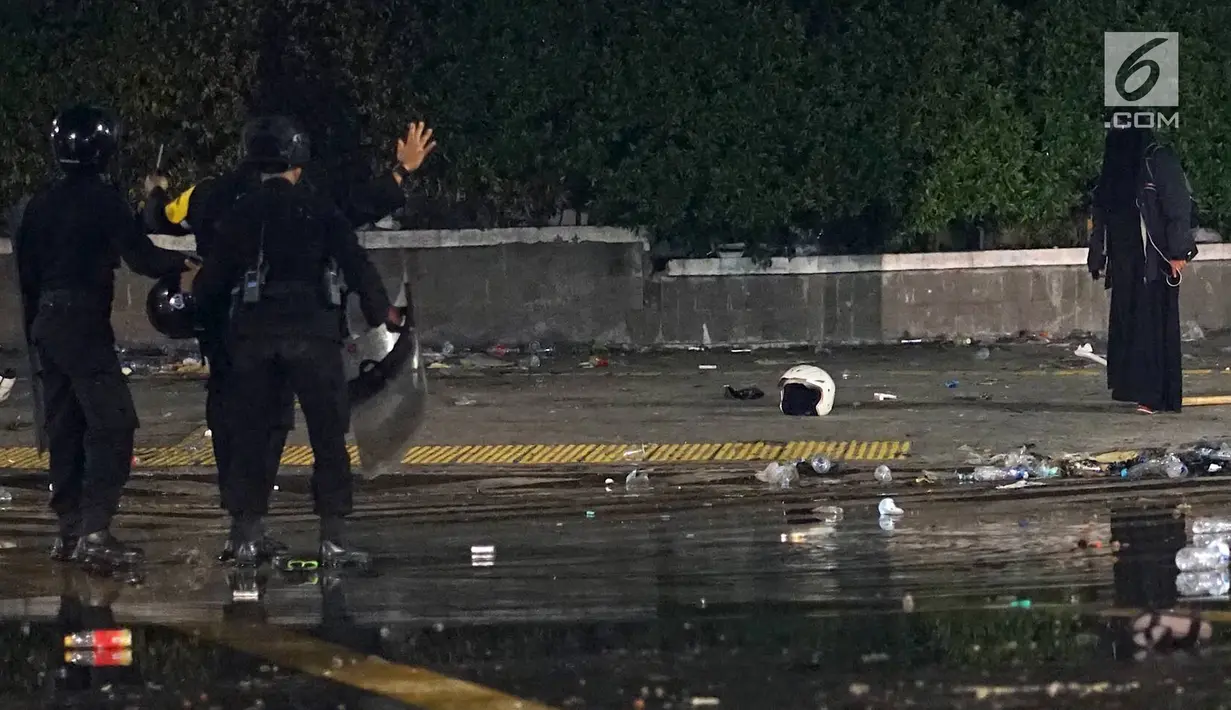 Aparat kepolisian dari Satuan Brimob berusaha menahan perempuan bercadar hitam dengan kabel menjuntai di tangan berusaha mendekat Gedung Bawaslu, Jakarta, Rabu (22/5/2019). Perempuan misterius yang berjalan sendiri tanpa massa ini mengenakan baju gamis warna hitam. (Liputan6.com/Immanuel Antonius)
