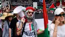 Aksi ini merupakan bagian dari gelombang protes berkelanjutan di Australia yang menuntut keadilan bagi warga Palestina di kota Gaza. Tampak dalam foto, para demonstran pro-Palestina membawa bendera, spanduk, dan plakat saat mereka berbaris berunjuk rasa di jalanan kota Sydney, Australia, Minggu 22 Februari 2026. (DAVID GRAY/AFP)