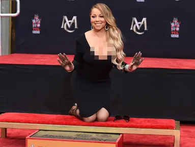 Penyanyi Mariah Carey berpose setelah membuat cetakan tangannya di TCL Chinese Theatre di Los Angeles, AS (1/11). Penyanyi 47 tahun ini mendapat penghargaan membuat cetakan tangan dan kaki di TCL Chinese Theatre. (Photo by Jordan Strauss/Invision/AP)