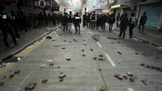 Sejumlah batu terlihat di belakang polisi anti huru hara setelah bentrokan dengan pengunjuk rasa di Mongkok, Hong Kong, Selasa (9/2). Bentrokan dimulai ketika pemerintah daerah mencoba untuk menertibkan PKL yang beroperasi. (REUTERS/Liau Chung-ren)