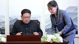 Pemimpin Korea Utara, Kim Jong-un menandatangani buku tamu di Peace House Panmunjom di samping adiknya, Kim Yo Jong sebelum melakukan pertemuan bersejarah dengan Presiden Korea Selatan, Moon Jae-in, Jumat (2/4). (Korea Summit Press Pool via AP)
