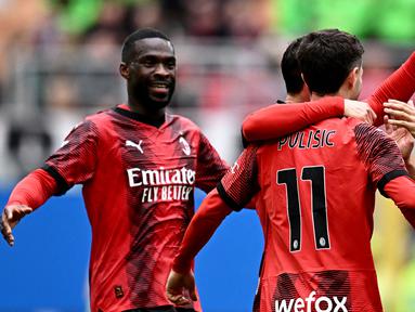 Bek AC Milan, Fikayo Tomori (kiri) bersama dan Noah Okafor (kanan) merayakan gol yang dicetak oleh Christian Pulisic (tengah) saat pertandingan sepak bola Serie A Italia di Stadion San Siro, Milan, 10 Maret 2024. (GABRIEL BOUYS/AFP)