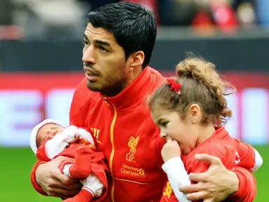 Striker Liverpool Luis Suarez membawa kedua putrinya menjelang pertandingan sepak bola Liga Inggris antara Liverpool vs Crystal Palace di stadion Anfield (05/10/13). (AFP/Paul Ellis)