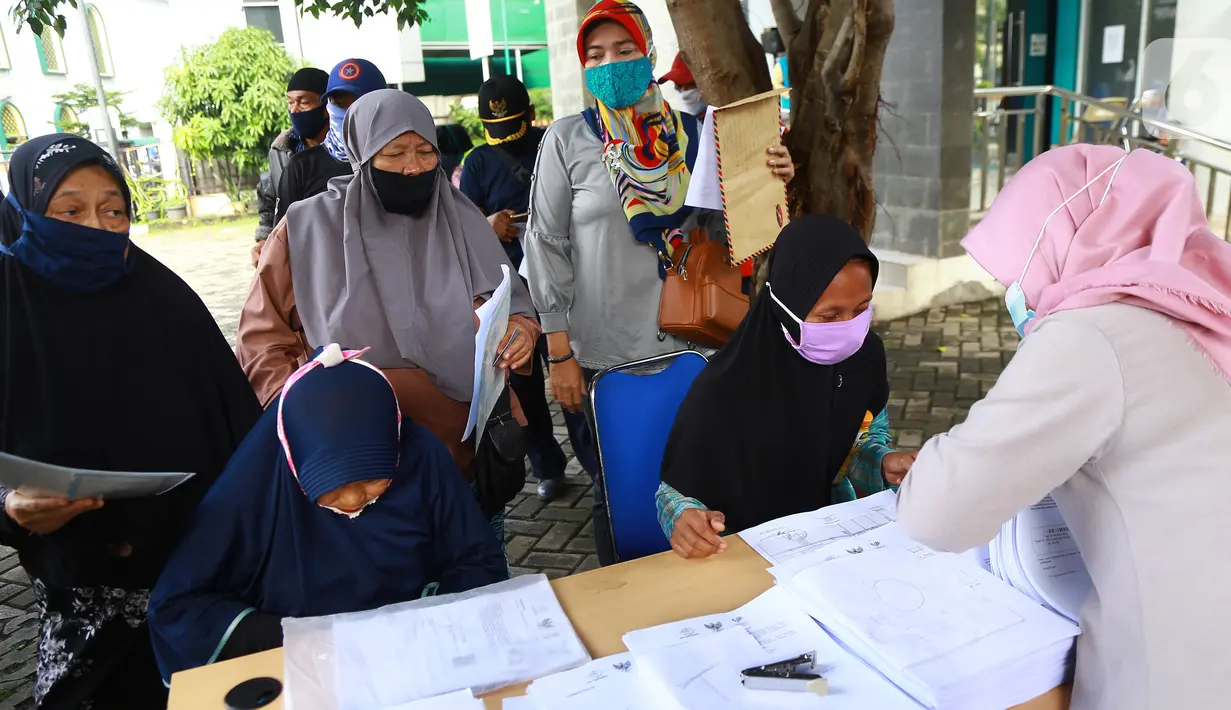 Warga antre menerima Bantuan Sosial Tunai (BST) di Kelurahan Pondok Benda, Kecamatan Pamulang, Tangerang Selatan, Minggu (10/01/2021). BST senilai Rp300 ribu akan disalurkan selama empat bulan berturut-turut mulai dari Januari - April 2021. (Liputan6.com/Fery Pradolo)