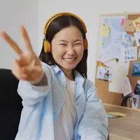 Seorang perempuan sedang berpose sambil mengenakan headphone (Foto Dok: Freepik/freepik).