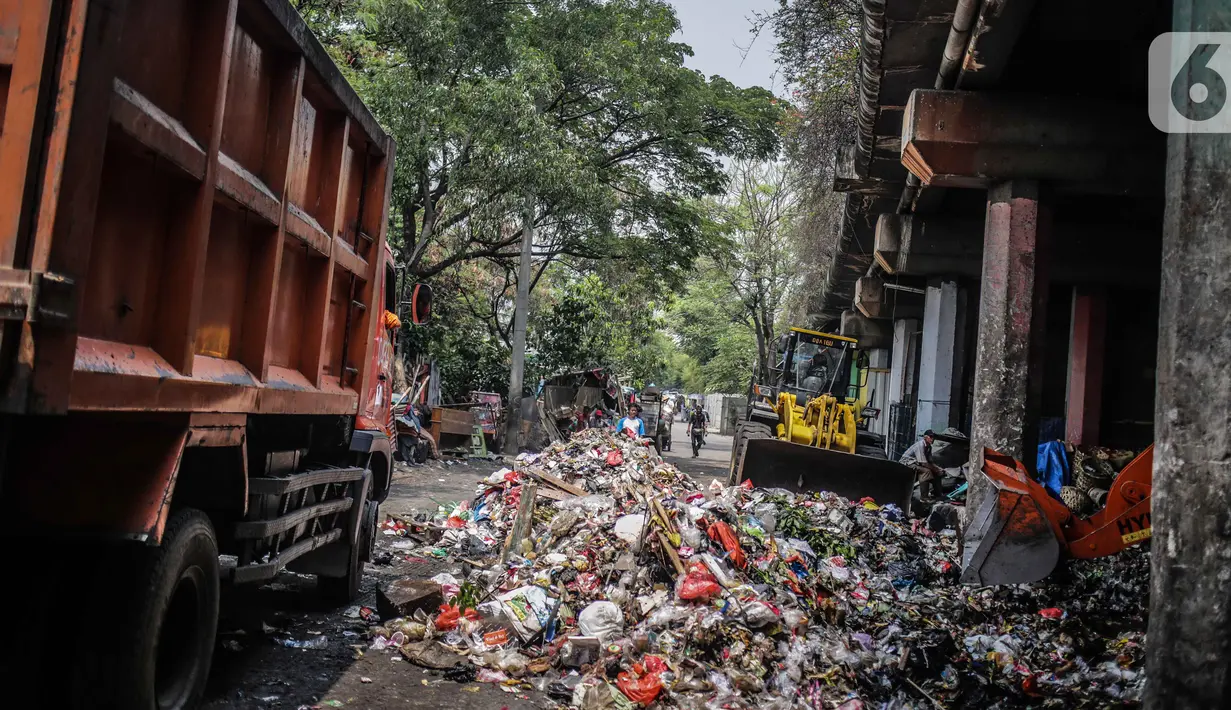 Petugas PPSU menggunakan kendaraan alat berat untuk mengangkut tumpukan sampah di kolong tol Wiyoto Wiyono, Tanjung Priok, Jakarta, Selasa (5/11/2019). Dalam sehari, petugas mengangkut sampah hingga 10 truk dengan berat total sekitar 100 ton ke TPA Bantar Gebang. (Liputan6.com/Faizal Fanani)