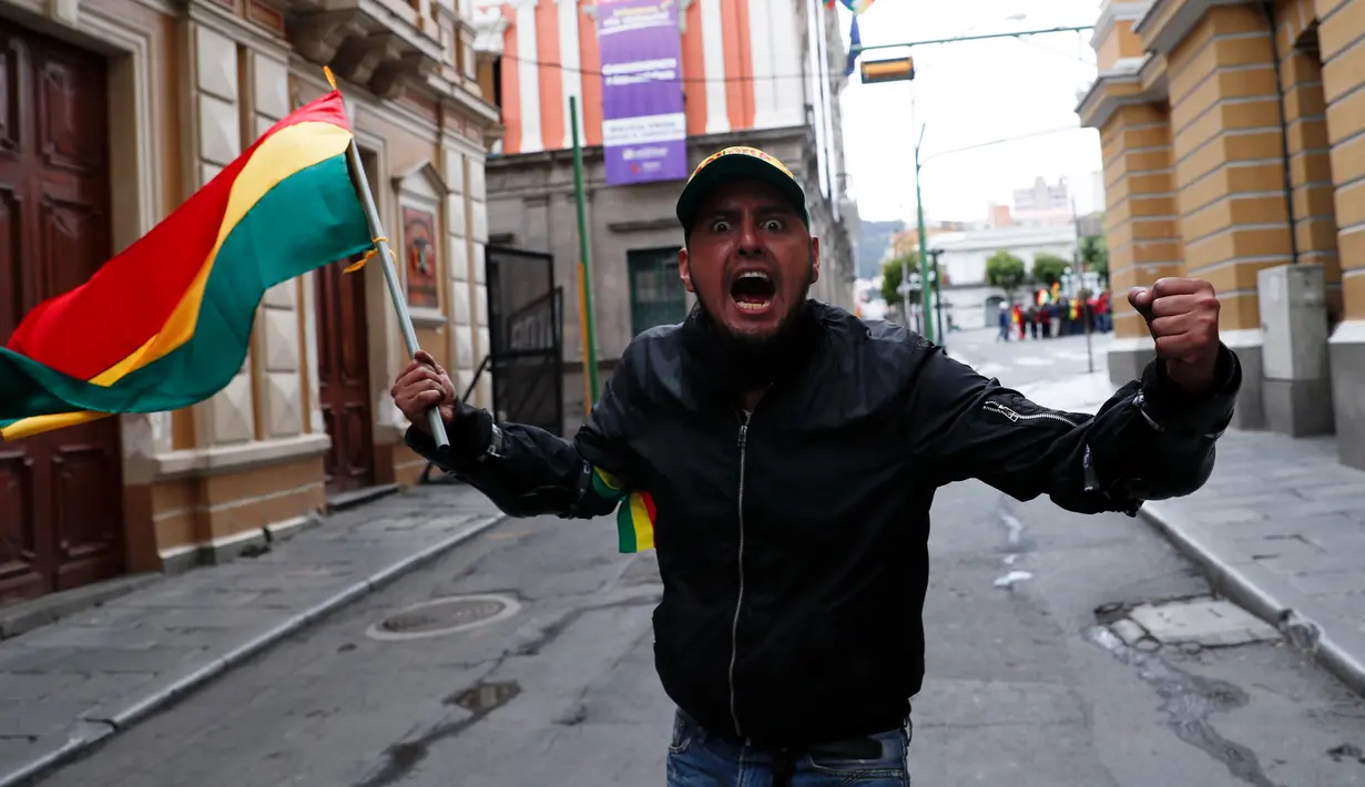 Seorang pria dengan bendera Bolivia merayakan pengunduran diri Presiden Evo Morales di La Paz, Minggu (10/11/2019). Morales yang telah memimpin Bolivia selama 14 tahun menyatakan mundur demi mengembalikan stabilitas keamanan usai diterpa gelombang unjuk rasa beberapa pekan terakhir. (AP/Juan Karita)