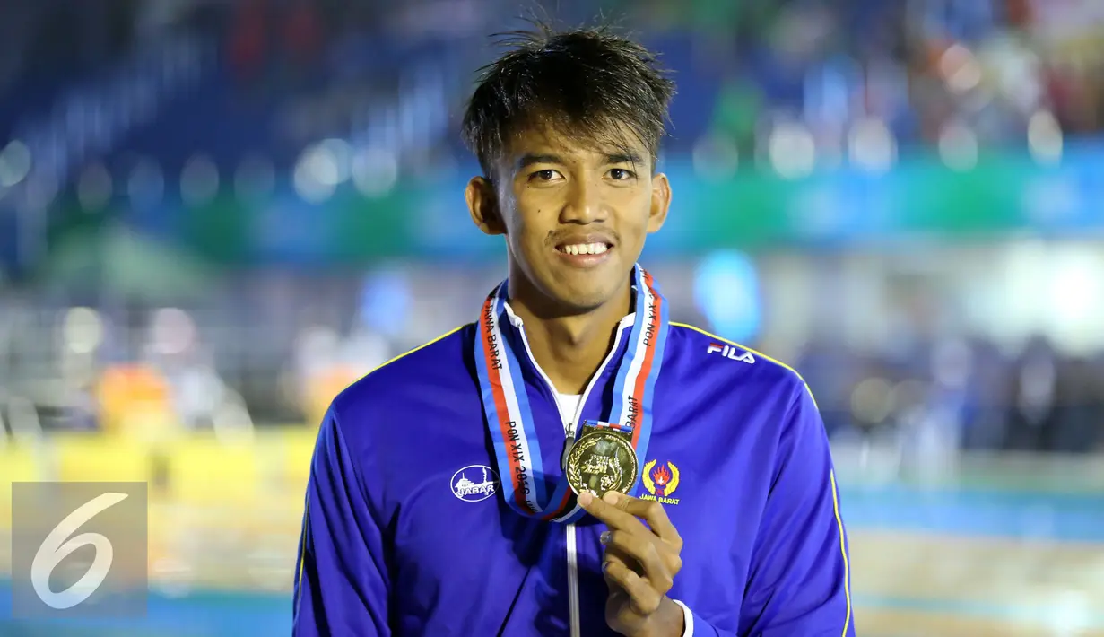 Perenang Jawa Barat, Triadi Fauzi S memamerkan medali kelas 100m gaya bebas putra di Gelanggang Renang FPOK UPI, Bandung, Senin (19/9). Triadi berhasil meraih emas sekaligus memecahkan rekor PON dengan 50,49 dtk. (Liputan6.com/Helmi Fithriansyah)