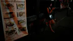 Seorang wanita terlihat di depan tempat hiburan malam di Bangkok, Thailand, (16/10). Sejumlah tempat hiburan malam memilih tutup dikarenakan untuk menghormati Sang Raja Bhumibol Adulyadej yang wafat. (REUTERS/Issei Kato)