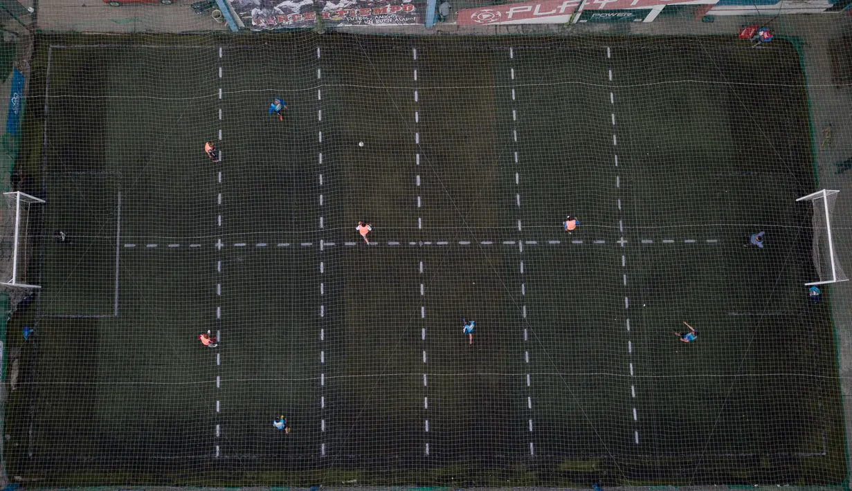 Sejumlah pria bermain sepak bola di klub lokal, Play Futbol 5, di Pergamino, Argentina, 1 Juli 2020. Demi bisa bermain di tengah pandemi Covid-19, klub membagi lapangan menjadi 12 persegi panjang untuk menandai area terbatas untuk setiap pemain, menjaga melakukan kontak fisik. (AP/Natacha Pisarenko)