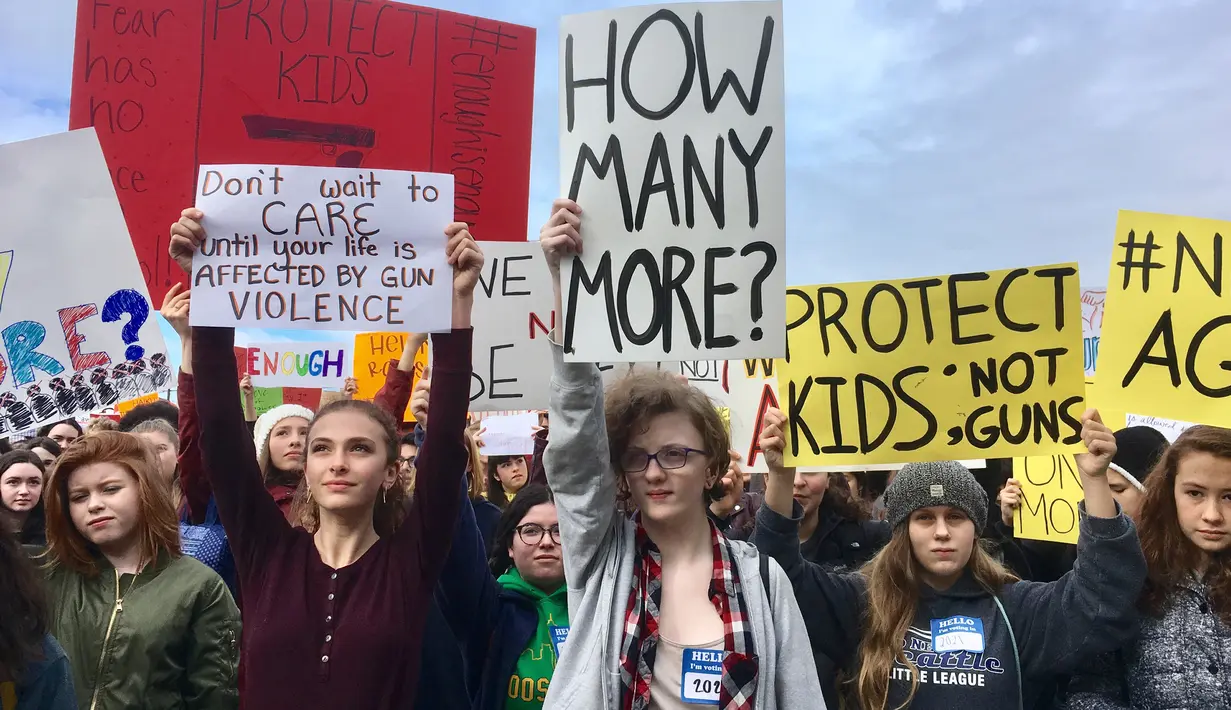 Sejumlah siswa dari Roosevelt High School membawa poster saat melakukan aksi di Seattle (14/3). Ini merupakan aksi terbesar pasca penembakan di sebuah SMA di Parkland, Florida, yang menewaskan 17 orang. (AP Photo / Manuel Valdes)