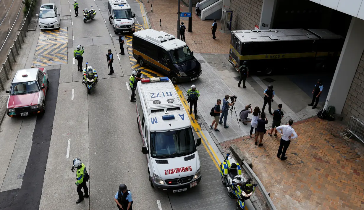 Polisi bersenjata lengkap menjaga mobil yang membawa mantan bankir Inggris, Rurik Jutting memasuki Pengadilan Tinggi di Hong Kong, Tiongkok, Selasa (25/10). Rurik didakwa atas pembunuhan dua warga negara Indonesia (WNI) di Hong Kong. (Reuters/Bobby Yip)