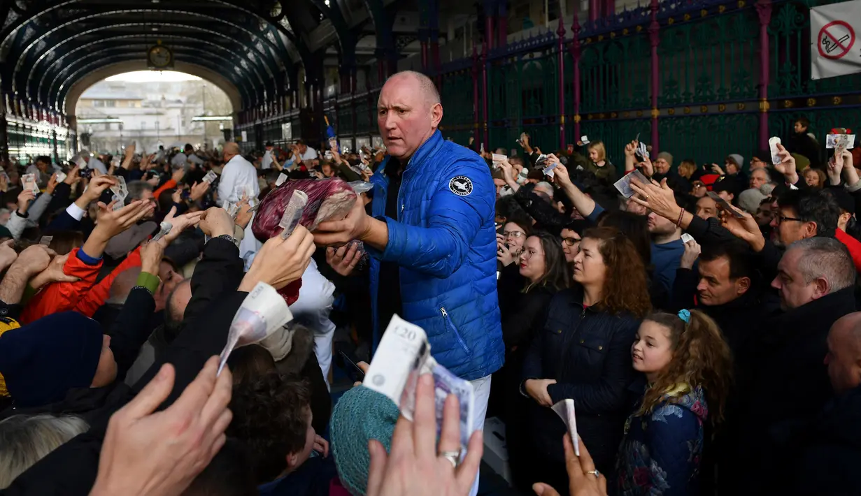Seorang penjual melelang potongan daging kepada pembeli yang memegang uang selama lelang tahunan menyambut malam Natal di Smithfield Market, London, Selasa (24/12/2019). Dalam tradisi yang hadir sejak 1800-an, calon pembeli bisa menawar harga daging tersebut.  (DANIEL LEAL-OLIVAS / AFP)
