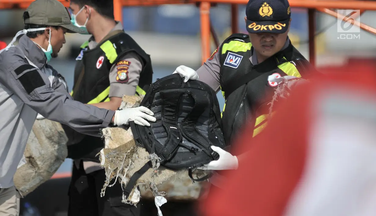 Polisi membawa tas korban jatuhnya pesawat Lion Air JT 610 di Tanjung Priok, Jakarta Utara, Senin (29/10). Petugas menemukan tas, sandal, pakaian, koper dan sebagainya. (Merdeka.com/Iqbal Nugroho)
