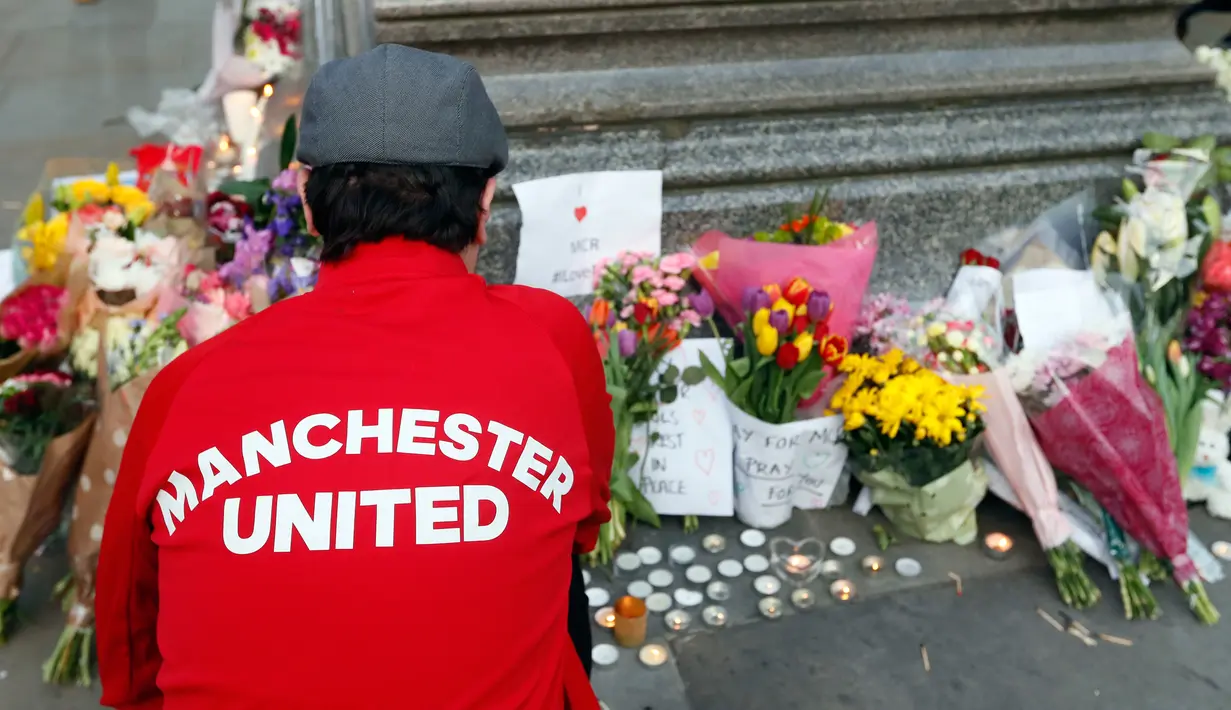 Seorang pria meletakan bunga di Albert Square, Manchester, Inggris, (23/5). Ribuan warga menunjukkan solidaritas terhadap korban bom di konser Ariana Grande dengan berdoa bersama serta meletakan bunga dan lilin. (AP Photo/Kirsty Wigglesworth)