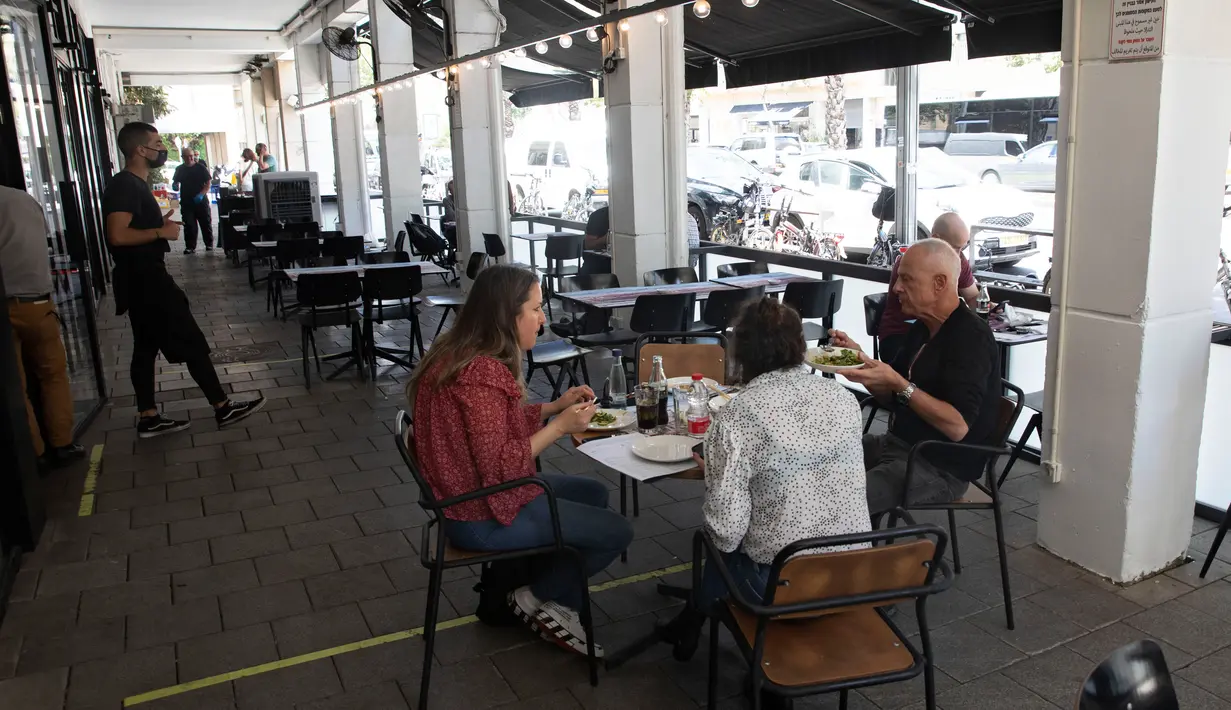 Pengunjung makan di luar di sebuah restoran di Tel Aviv, Israel pada Rabu (27/5/2020). Setelah lebih dari dua bulan ditutup untuk membendung penularan virus corona, restoran hingga kafe di Israel diizinkan dibuka kembali hari Rabu, 27 Mei. (AP Photo/Sebastian Scheiner)