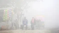 Warga duduk di samping toko saat kabut tebal akibat polusi menyelimuti  Delhi, India (1/12). Kabut ini diklaim sebagai kabut asap terparah yang dialami oleh New Delhi dalam 17 tahun yang telah mengurangi jarak pandang. (REUTERS/Cathal McNaughton)