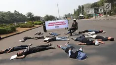 Aktivis berbaring saat menggelar aksi #BersihkanIndonesia di depan Istana Merdeka, Jakarta, Senin (19/8/2019). Aktivis menyerukan kebebasan hakiki dari kerusakan lingkungan dengan meninggalkan sumber energi fosil dari batu bara kotor beralih ke energi bersih terbarukan. (Liputa6.com/Angga Yuniar)