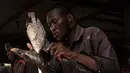 Pedagang ikan yang telah bekerja sejak berusia tujuh tahun dan sekarang menjadi mahasiswa memotong ikan di sebuah pasar ikan di dekat Sungai Nil, di kota kembar Khartoum, Omdurman (24/6/2019). (AFP Photo/Yasuyoshi Chiba)