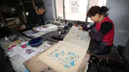 Pekerja menyelesaikan pembuatan gambar untuk tahun baru Imlek di sebuah lokakarya di Weifang di provinsi Shandong, Tiongkok (20/1). Mereka membuat gambar untuk perayaan Imlek ini secara manual. (AFP)