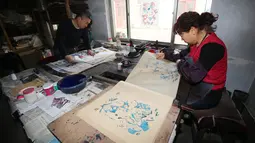 Pekerja menyelesaikan pembuatan gambar untuk tahun baru Imlek di sebuah lokakarya di Weifang di provinsi Shandong, Tiongkok (20/1). Mereka membuat gambar untuk perayaan Imlek ini secara manual. (AFP)