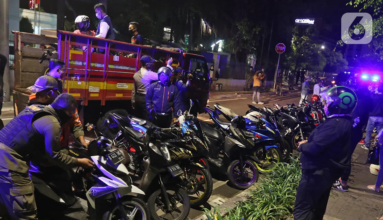 Petugas gabungan bersiap membawa motor pelanggar protokol kesehatan COVID-19 pada patroli penegakkan di Jalan Veteran, Jakarta Pusat, Sabtu (26/12/2020). Dalam kegiatan itu, sejumlah pemuda diamankan untuk dilakukan Rapid Test secara massal dan sanksi menyapu. (Liputan6.com/Herman Zakharia)