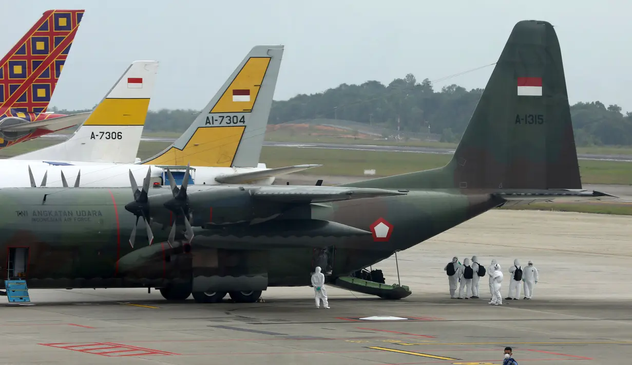 Petugas mengenakan pakaian pelindung turun dari pesawat hercules saat tiba bandara internasional Hang Nadim, Batam, Minggu (2/2/2020). Korban meninggal dunia akibat Virus Corona di seluruh wilayah daratan China hingga Minggu (2/2/2020) pagi telah mencapai 304 orang. (AFP/Ricky Prakoso)