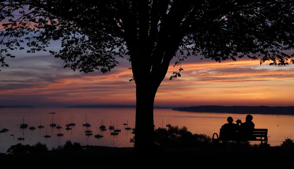 Pasangan menikmati teluk Casco saat matahari di Portland, Maine (21/8/2019). Casco Bay adalah saluran masuk Teluk Maine di pantai selatan Maine, New England, Amerika Serikat. (AP Photo/Robert F. Bukaty)