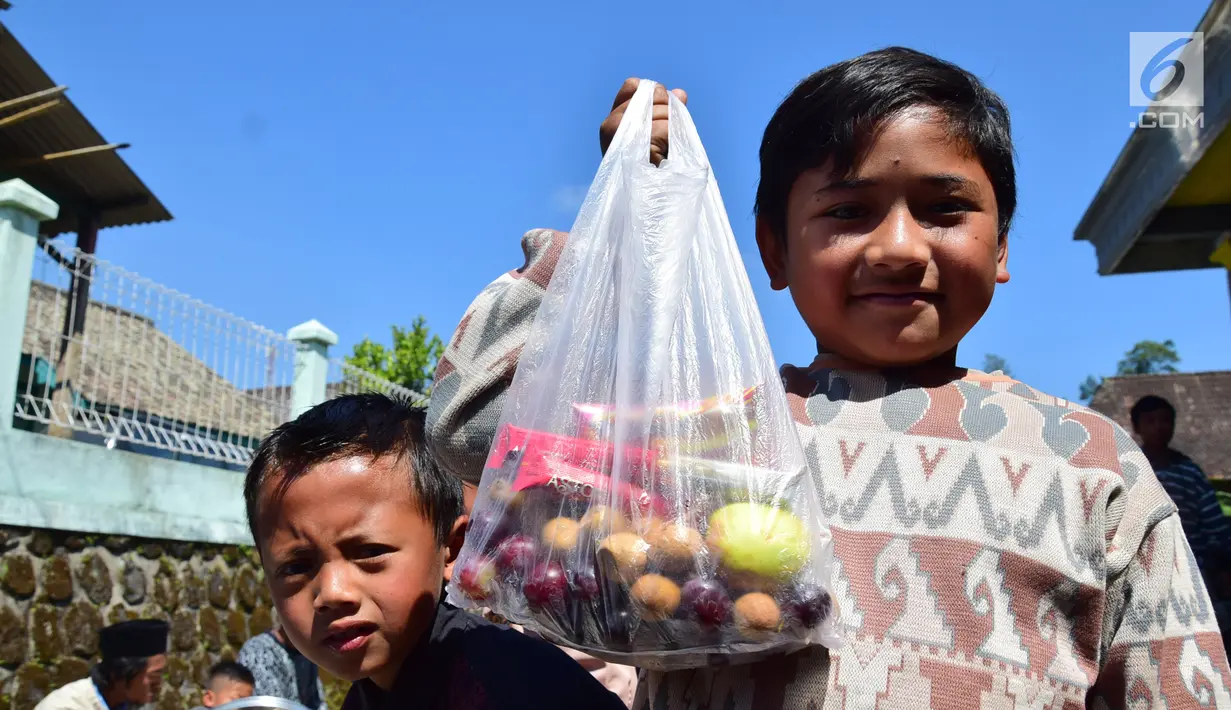 Seorang anak menunjukkan makanan di Kabupaten Boyolali, Kamis (3/5). Tradisi ini Sebagai perayaan menyambut datangnya bulan ramadan, kemudian dilanjutkan makan bersama di pertigaan jalan desa. (Liputan6.com/Gholib)