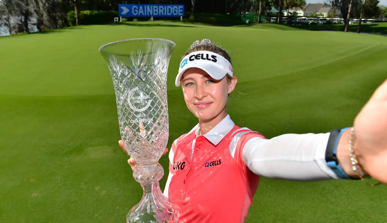 Nelly Korda meniru gaya swafoto berpose dengan trofi usai menjuarai final LPGA Gainbridge di Lake Nona Golf and Country Club, Minggu (28/2/2021). (Foto: AFP/Getty Images/Julio Aguilar)